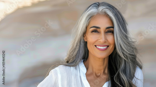 A happy mature woman enjoys the warmth of the sun, her radiant smile contrasting against a serene desert backdrop.