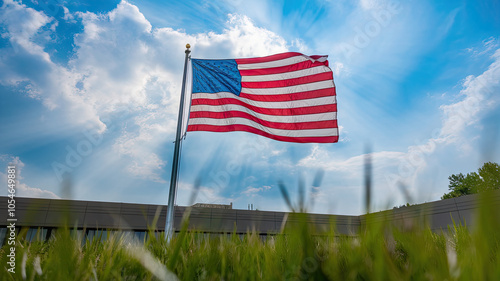 A vibrant U.S. flag waves proudly against a bright sky, surrounded by lush green grass, symbolizing freedom and patriotism.