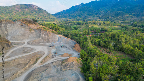 In this striking landscape, heavy machinery dominates as it excavates the mountainside, revealing hidden treasures within. Dust clouds rise from the intense operation, showcasing the powerful intersec