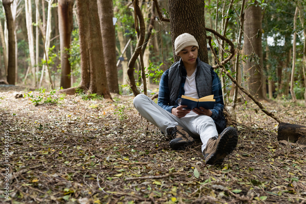 Young man reading book while relaxing in peaceful forest setting Young man reading book while relaxing in peaceful forest setting