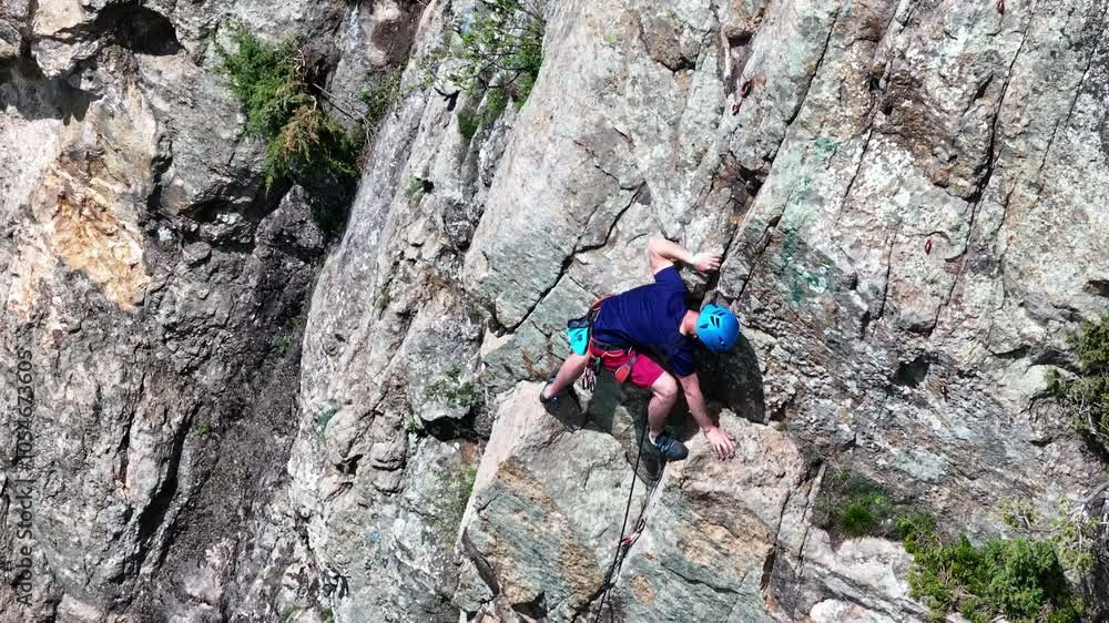 Determined climber skillfully ascending a steep rock face Determined climber skillfully ascending a steep rock face