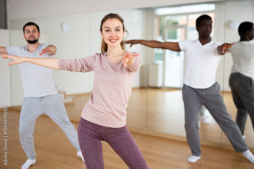 Fototapeta premium Woman and men dancing in fitness studio. Aerobic dance group practice.