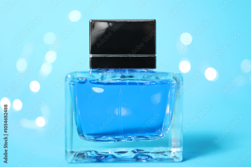 Perfume bottle on light blue background with blurred lights, closeup Perfume bottle on light blue background with blurred lights, closeup
