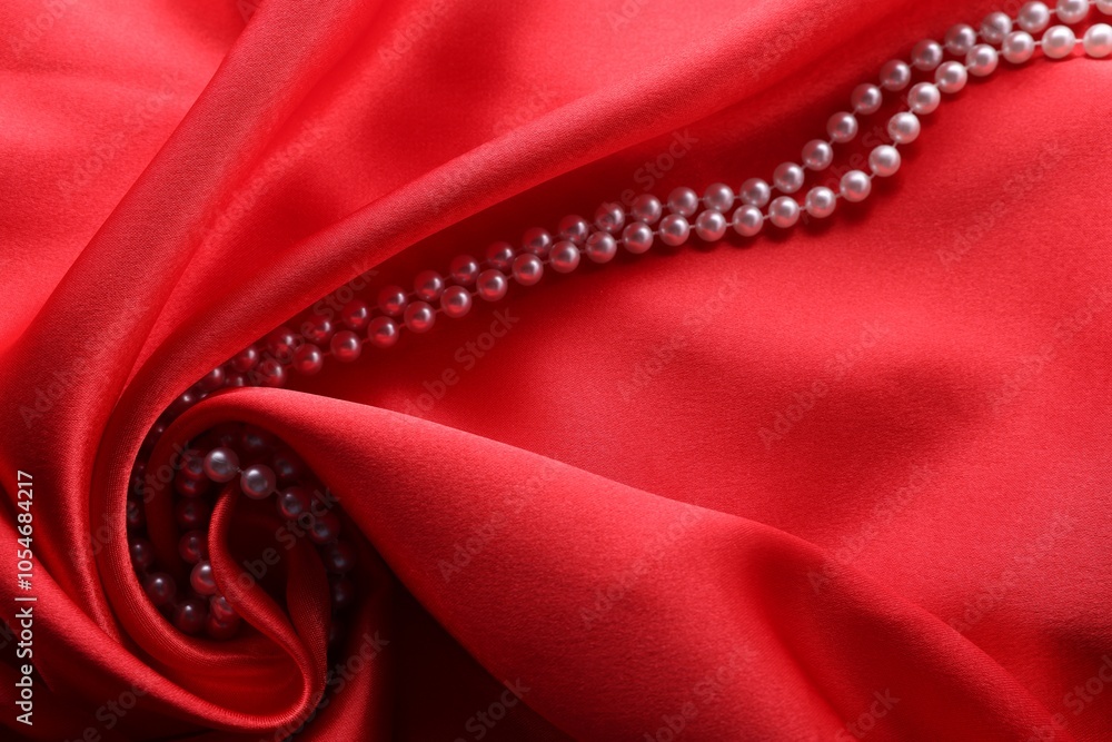 Beautiful pearl necklace on red cloth, above view Beautiful pearl necklace on red cloth, above view