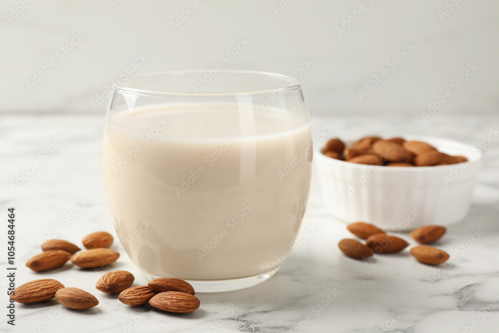 Glass of almond milk and nuts on white marble table, closeup Glass of almond milk and nuts on white marble table, closeup