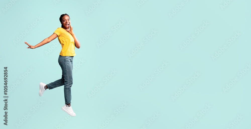 Cheerful African Woman Shouting Jumping In Air Holding Hand Near Mouth On Blue Background. Studio Shot, Free Space Cheerful African Woman Shouting Jumping In Air Holding Hand Near Mouth On Blue Background. Studio Shot, Free Space