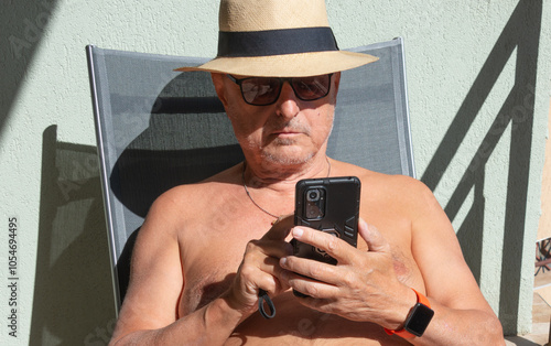 Man scrolling on the mobile while sunbathing #1054694495