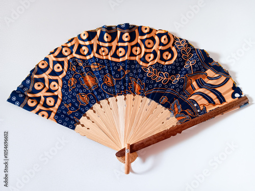 Indonesian traditional hand fan or folding fan with bamboo handle and batik pattern fabric isolated on white background. photo