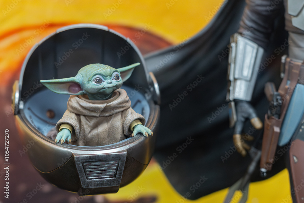 Fototapeta premium 8th Comic Con Convention In GUAYAQUIL, ECUADOR - AUG 06, 2023 - Grogu (Baby Yoda) figurine in hover cradle with Mandalorian beside, capturing Star Wars essence for sci-fi collectors and fans.