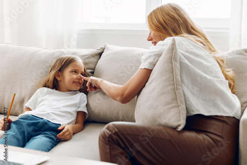 Mother and daughter sharing a special moment on a cozy couch in a bright, welcoming living room