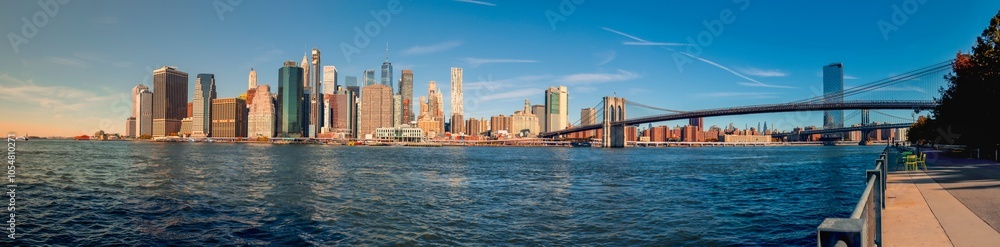 Naklejka premium DowntownManhattan Skyline with Brooklyn Bridge: A stunning view showcasing iconic skyscrapers and the historic bridge, beautifully illuminated at sunset, reflecting the vibrant energy of New York City