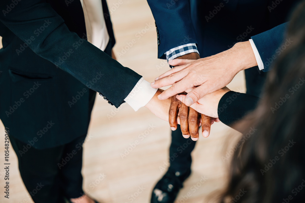 Colleagues from various ethnicities and backgrounds join hands in a modern office, emphasizing teamwork, cooperation, and community. An above view showcases their commitment to equality and diversity. Colleagues from various ethnicities and backgrounds join hands in a modern office, emphasizing teamwork, cooperation, and community. An above view showcases their commitment to equality and diversity.