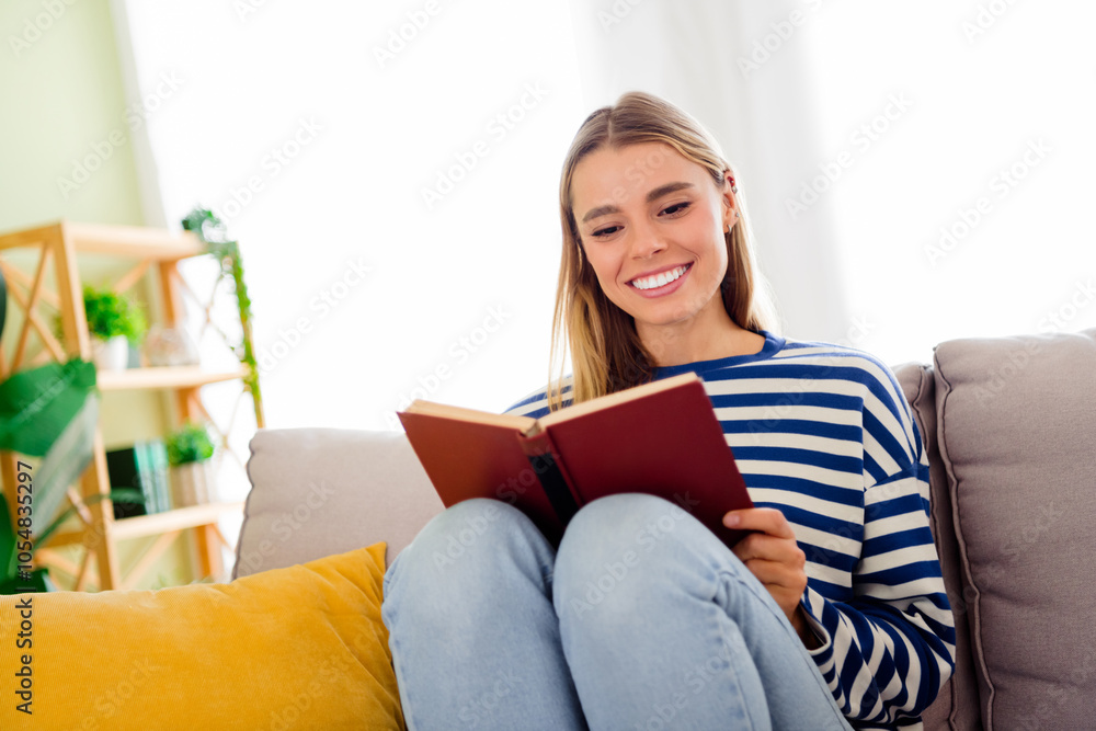 Photo of lovely blonde young girl read book sit couch dressed striped garment spacious house indoors room Photo of lovely blonde young girl read book sit couch dressed striped garment spacious house indoors room