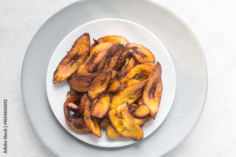 Overhead view of fried plantains on a white plate. Top view of fried ripe plantains on a plate Overhead view of fried plantains on a white plate. Top view of fried ripe plantains on a plate