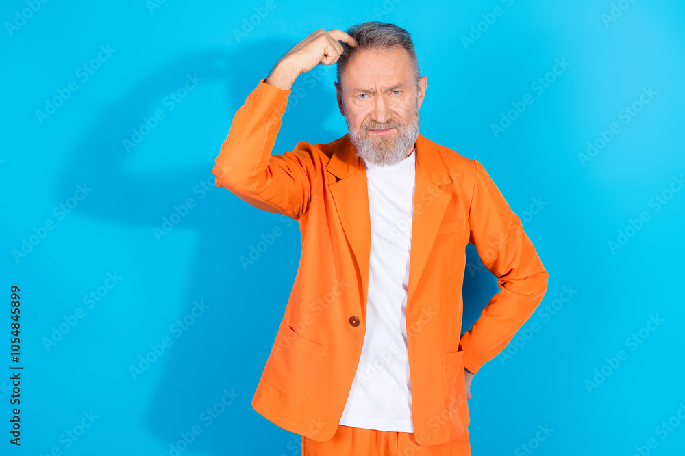 Portrait of modern stylish aged man scratch head think empty sapce wear orange costume isolated on blue color background Portrait of modern stylish aged man scratch head think empty sapce wear orange costume isolated on blue color background