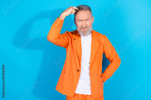 Portrait of modern stylish aged man scratch head think empty sapce wear orange costume isolated on blue color background