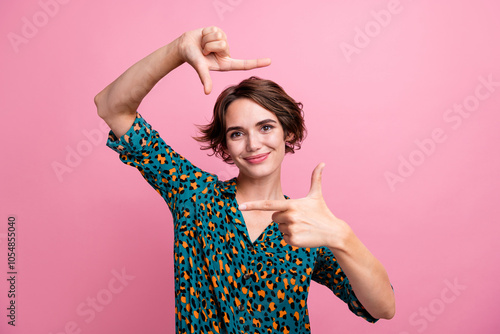 Portrait of good mood adorable woman with bob hairdo wear print blouse fingers showing photo frame isolated on pink color background