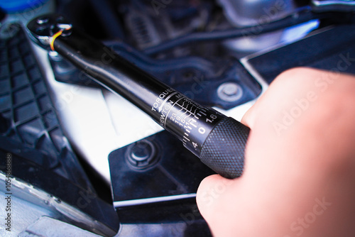 Obraz na płótnie Close up of the torque wrench adjuster in a hand over car engine , Car mechanic tools concept w salonie