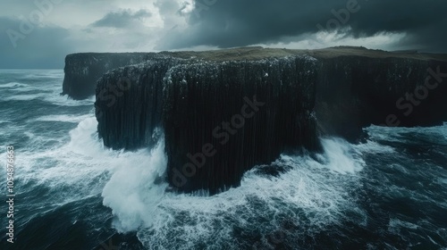 Aerial shot of Fingal's Cave during a storm, with crashing waves against the cliffs and dark clouds enhancing the dramatic atmosphere. No people included. photo