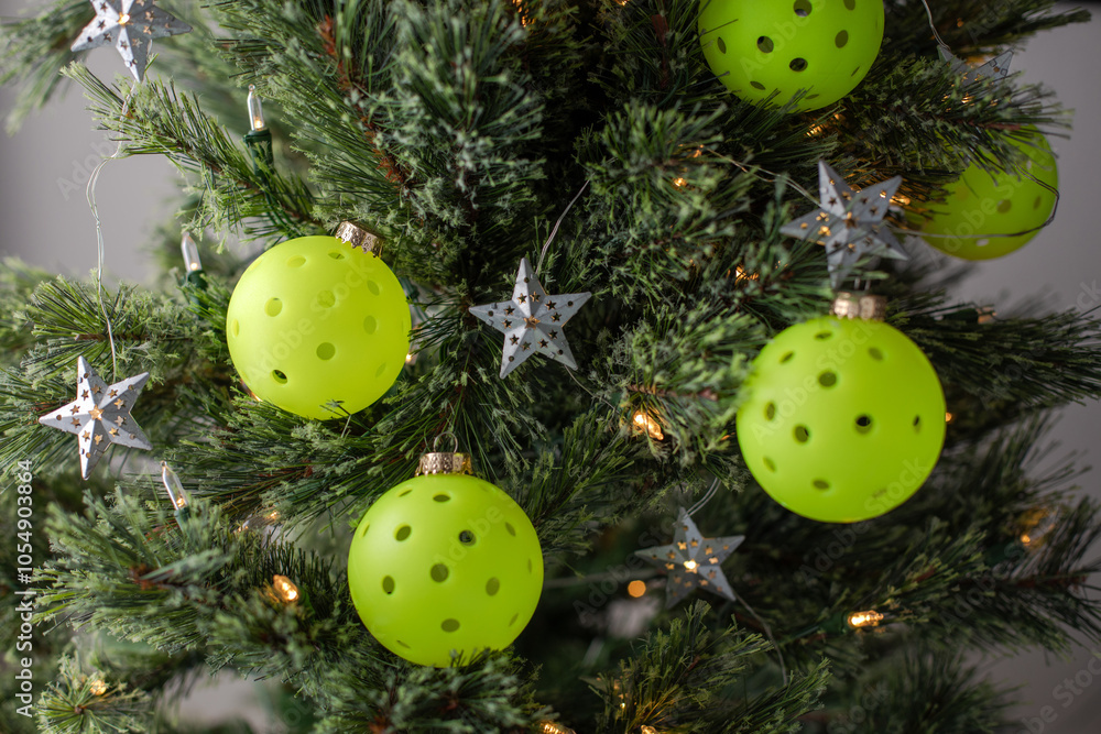 Fototapeta premium Close view of a Christmas tree decorated with pickleballs as ornaments and shining lights and stars. Selective focus. Pickleball Christmas tree backdrop.