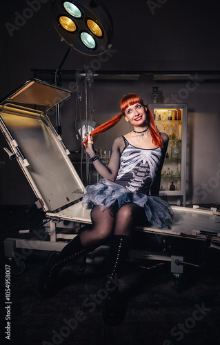 Red-haired beautiful woman smiles in an eerie hospital room, wearing rugged boots and a gothic Halloween dress