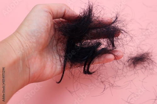 Hair loss or alopecia on woman's hand close up. With a pink background.
