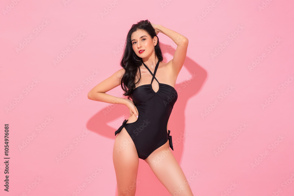 Summer studio shot portrait of young beautiful Caucasian woman wearing black summer swimsuit standing and posing in pink color isolated background Summer studio shot portrait of young beautiful Caucasian woman wearing black summer swimsuit standing and posing in pink color isolated background