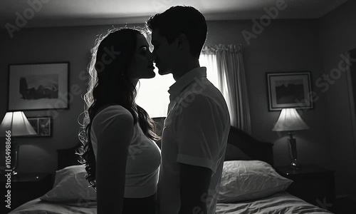 Silhouette of a couple embracing in a softly lit bedroom.