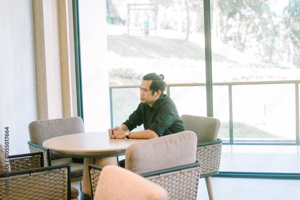 Man sitting in a hotel lobby, relaxed and contemplative, surrounded by modern decor Man sitting in a hotel lobby, relaxed and contemplative, surrounded by modern decor