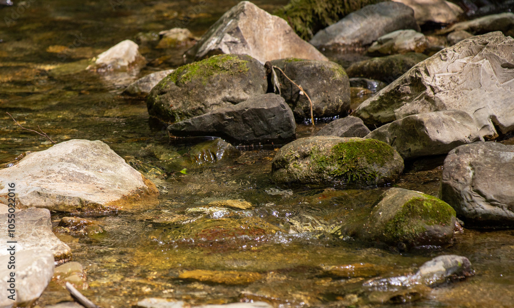 A stream of water flows between large rocks A stream of water flows between large rocks
