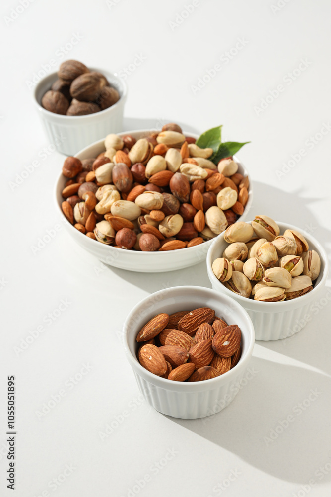 Various nuts in white bowls on a white background Various nuts in white bowls on a white background
