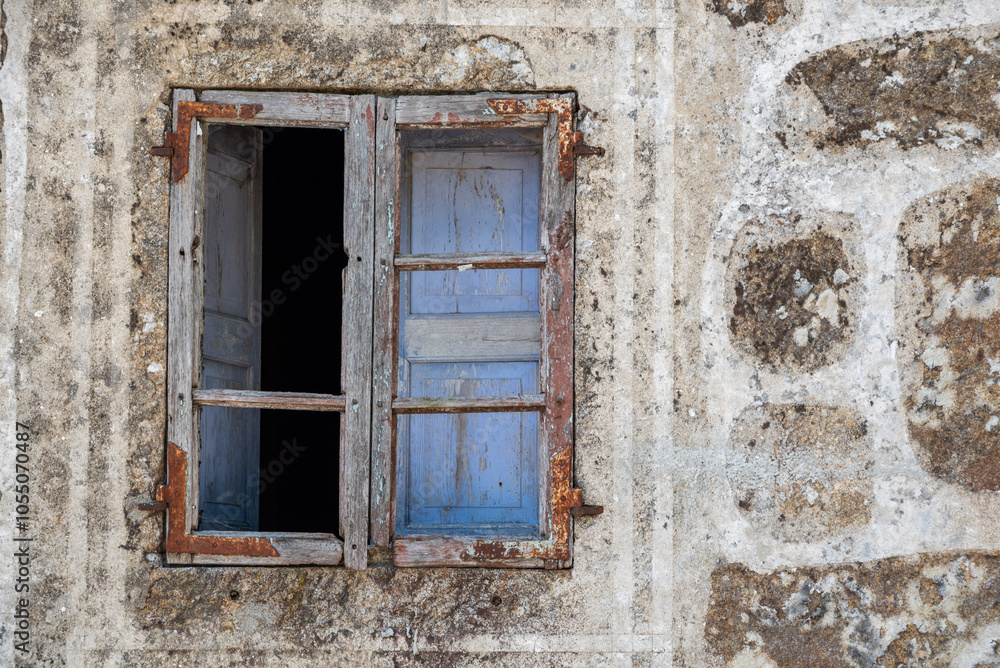 Picturesque rustic old window with wooden frames and blue shutters in a stone house Picturesque rustic old window with wooden frames and blue shutters in a stone house