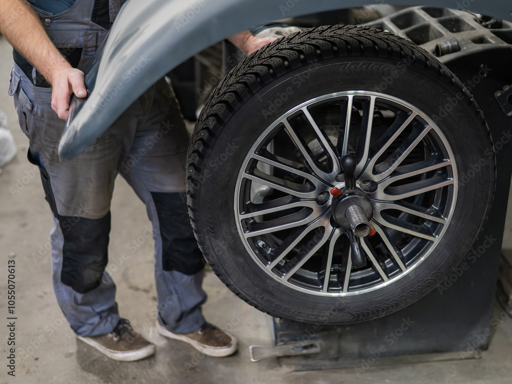 Mechanic balancing a wheel in a workshop. Mechanic balancing a wheel in a workshop.