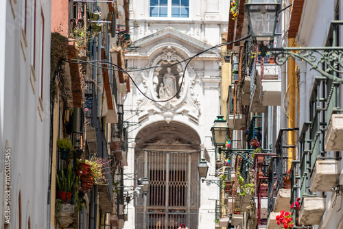 Narrow Rua Vale with picturesque facades and balconies, portal of church Nossa Senhora das Merces in the background