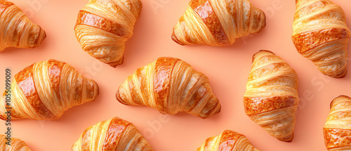 Obraz na płótnie Golden brown croissants arranged on a pastel orange background, showcasing their flaky layers and appetizing texture. w salonie
