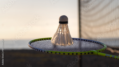 Close-up of a badminton racket with a shuttlecock on the background of a net on a beach court, copy space. Badminton sports