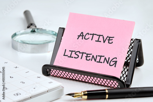 Business concept. Phrase, text,words ACTIVE LISTENING is written on a pink sticker on a black stand on a gray background