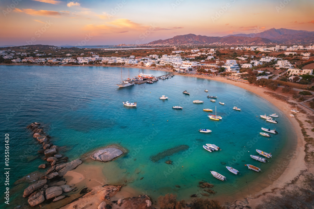 A serene beach on Paros Island, Greece, with golden sands, clear turquoise waters, and gentle waves. Framed by rocky cliffs and lush greenery, it's an idyllic Mediterranean escape under the sun.