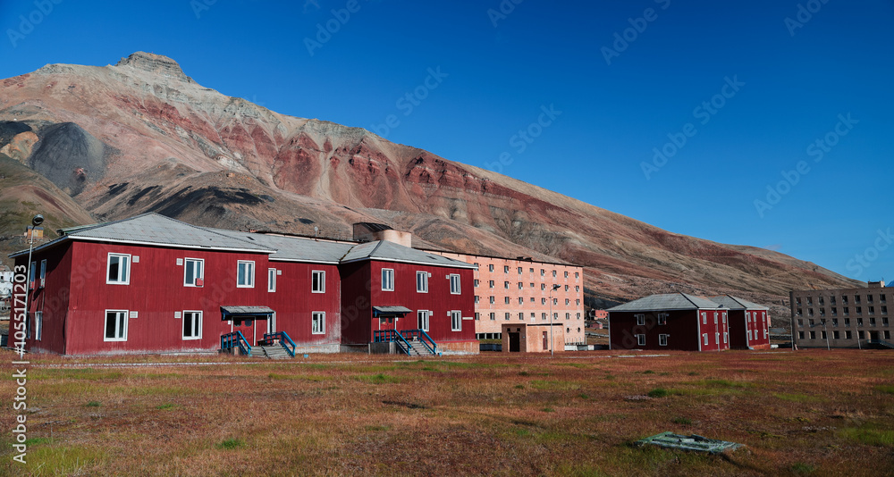 Exploring the abandoned buildings of Pyramiden in Svalbard under a clear blue sky