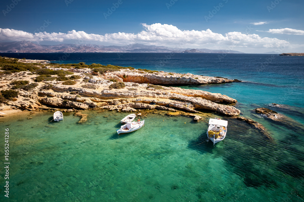 A serene beach on Paros Island, Greece, with golden sands, clear turquoise waters, and gentle waves. Framed by rocky cliffs and lush greenery, it's an idyllic Mediterranean escape under the sun.