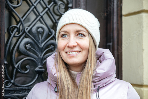 Smiling woman in winter attire standing by ornate door