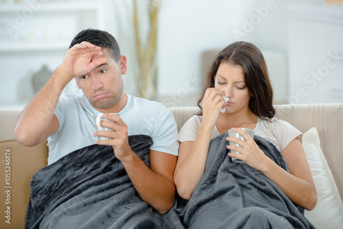 young couple blowing their nose in tissue at home photo