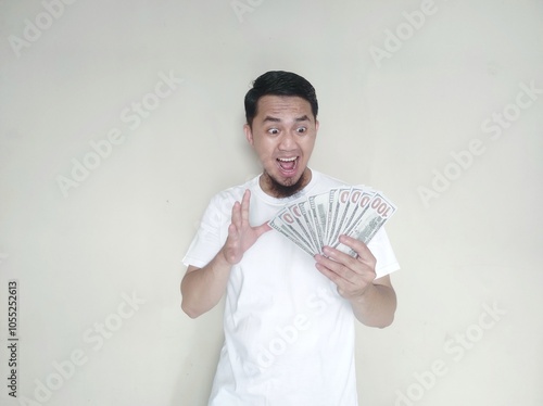 Adult Asian man showing excited face expression when looking to US dollar money that he hold photo