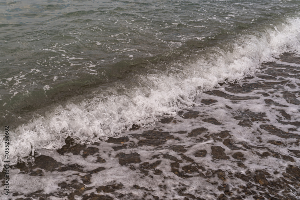 Sea waves on the pebble beach. Blue sea surface with waves. Abstract background of water flow in ocean, sea, river, lake. Seascape wallpaper. Sea waves on the pebble beach. Blue sea surface with waves. Abstract background of water flow in ocean, sea, river, lake. Seascape wallpaper.