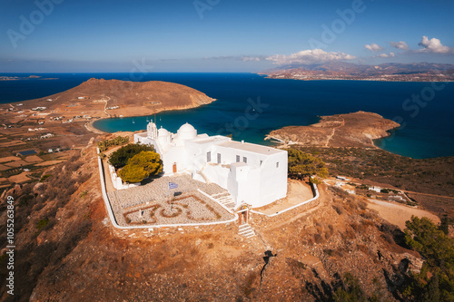 A charming blue-domed chapel on Paros Island, Greece, set against the backdrop of the shimmering Aegean Sea. The whitewashed walls, vibrant dome, and surrounding stone path create a picturesque scene 