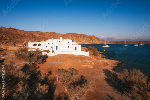 Obraz na płótnie A charming blue-domed chapel on Paros Island, Greece, set against the backdrop of the shimmering Aegean Sea. The whitewashed walls, vibrant dome, and surrounding stone path create a picturesque scene w salonie