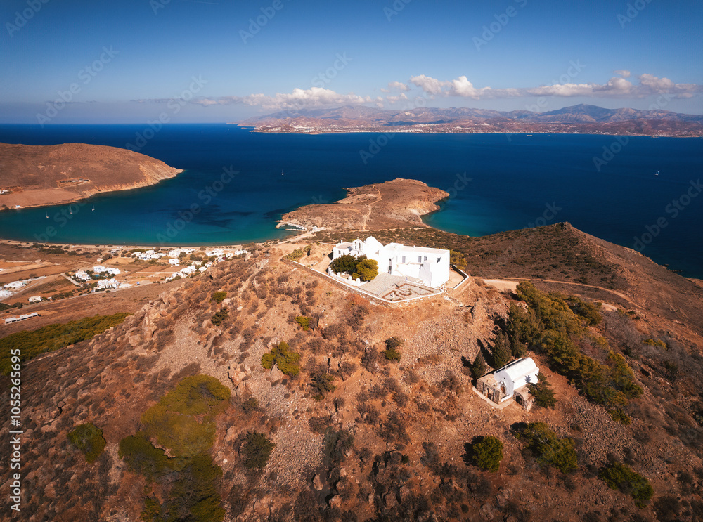 A charming blue-domed chapel on Paros Island, Greece, set against the backdrop of the shimmering Aegean Sea. The whitewashed walls, vibrant dome, and surrounding stone path create a picturesque scene