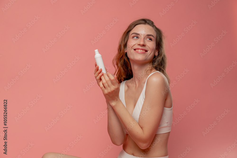 close up studio beauty shoot on pink background long-haired girl sitting posing in underwear with white tube of cream natural beauty close up studio beauty shoot on pink background long-haired girl sitting posing in underwear with white tube of cream natural beauty