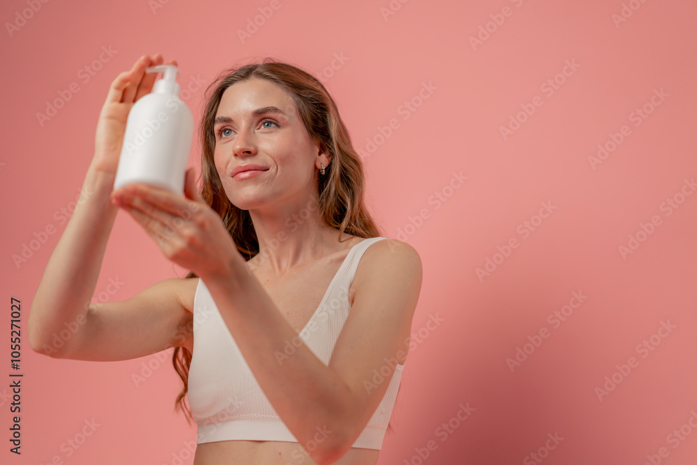 studio beauty shoot on pink background long-haired girl sitting posing in underwear with a lotion dispenser container natural beauty studio beauty shoot on pink background long-haired girl sitting posing in underwear with a lotion dispenser container natural beauty
