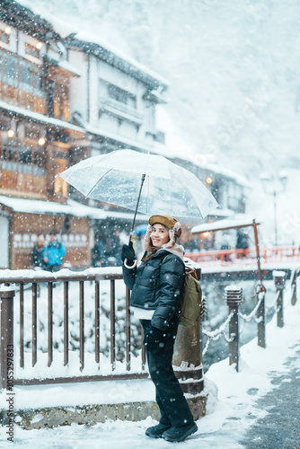 Woman tourist Visiting Ginzan Onsen in Yamagata, happy Traveler sightseeing Japanese Onsen village with Snow in winter season. landmark and popular for attraction in Japan. Travel and Vacation concept photo